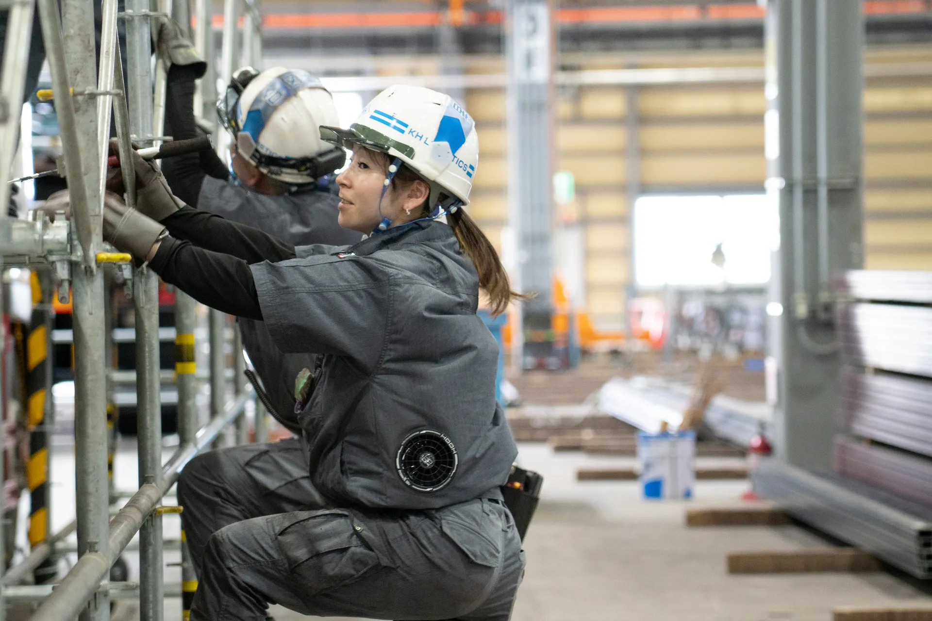 女性社員が、足場の組み立て作業を行っている