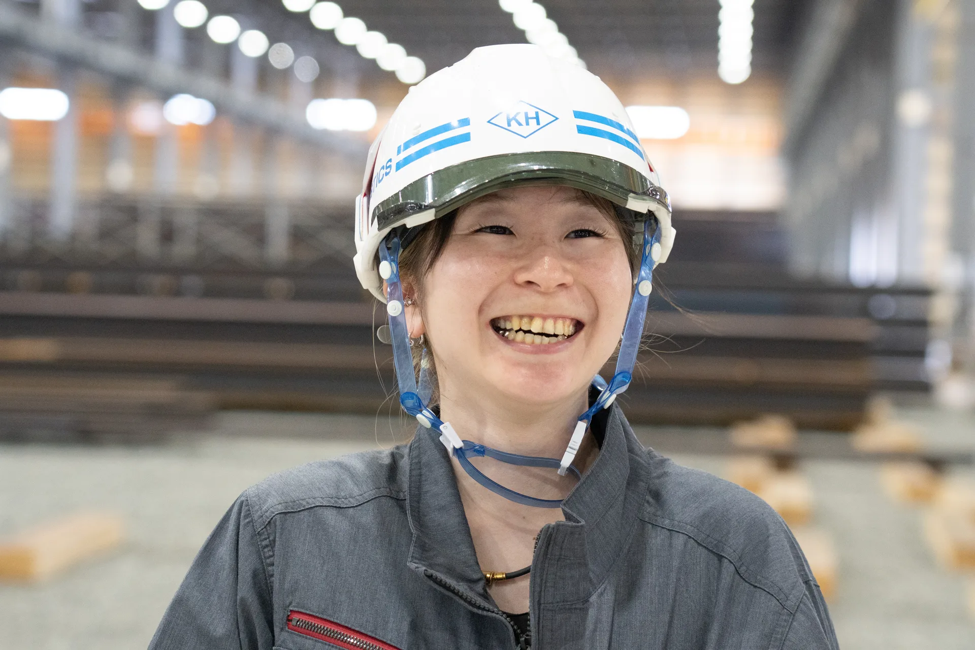 ヘルメット姿の女性社員が、明るい笑顔を見せている