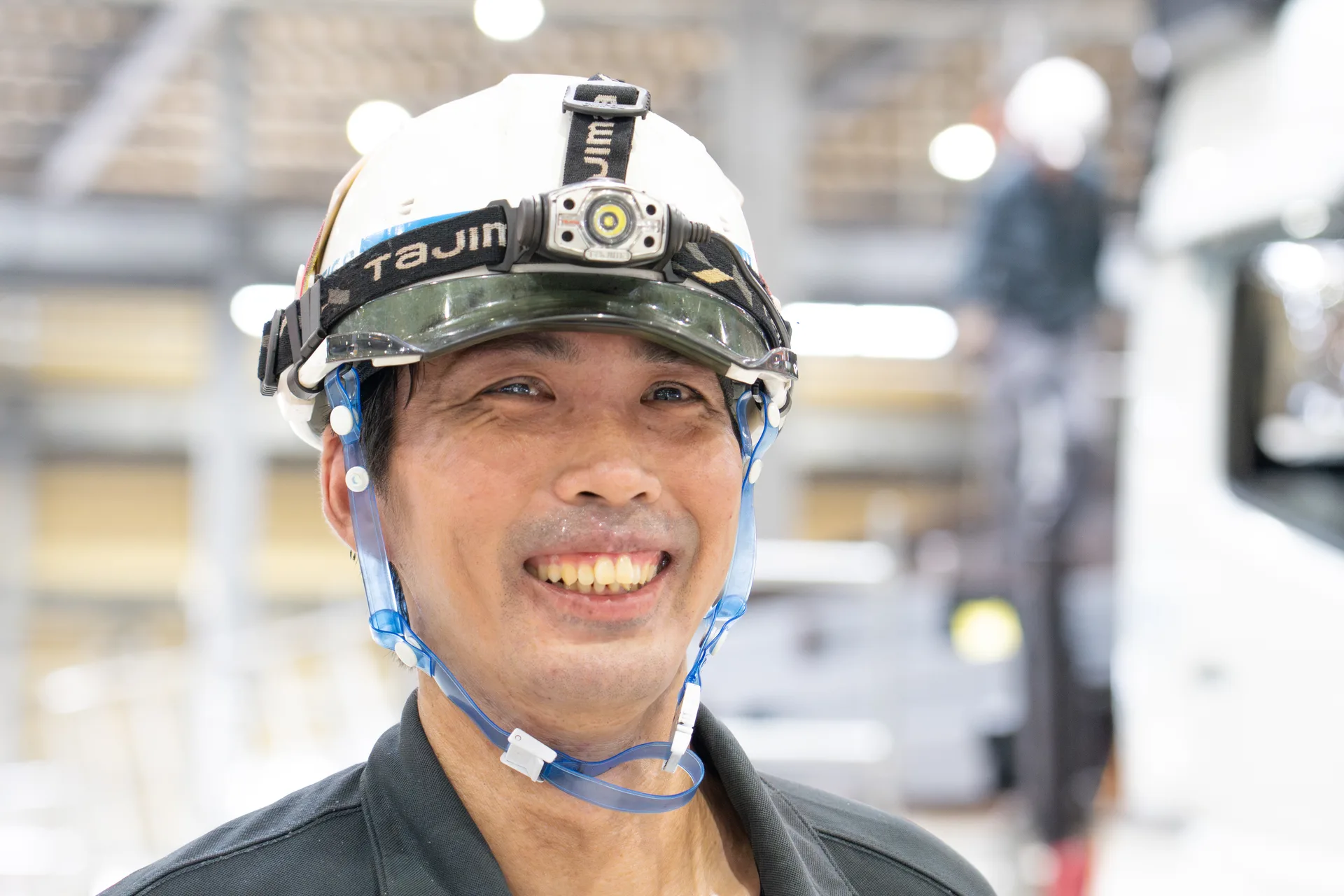 ヘルメット姿の男性社員が、笑顔を見せている