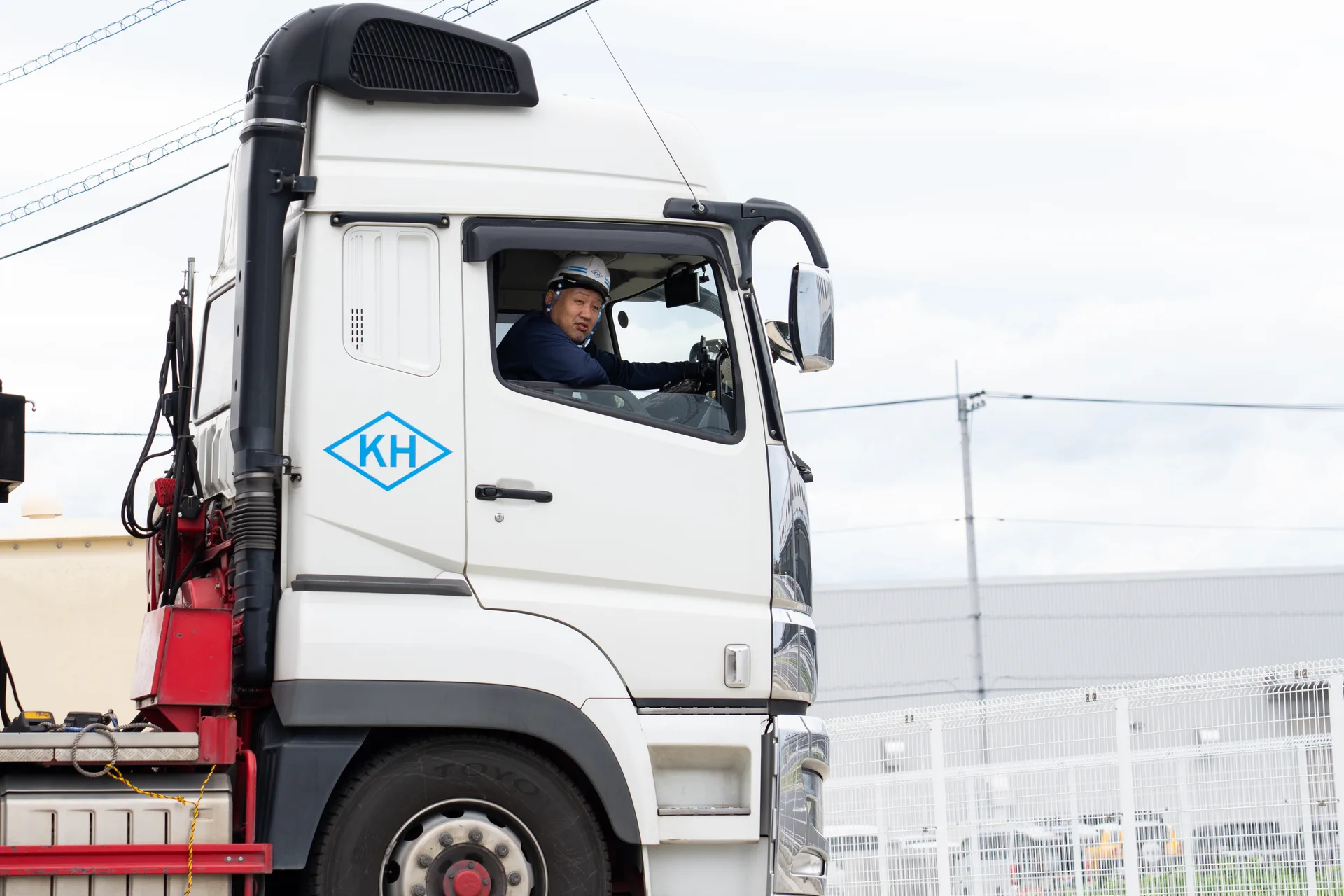 トラックの運転席から、男性ドライバーが笑顔でこちらを見ている