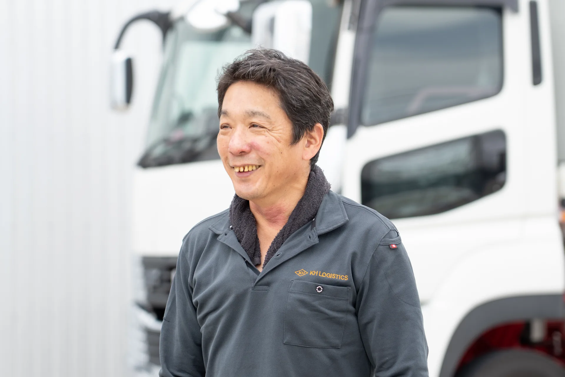 KH LOGISTICSのトラックの前で、男性社員が笑顔を見せている